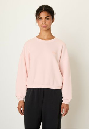 Lichtroze sweatshirt met een ronde hals, lange mouwen en een licht cropped zoom. Voorzien van een subtiele logodetail in bijpassende kleur.