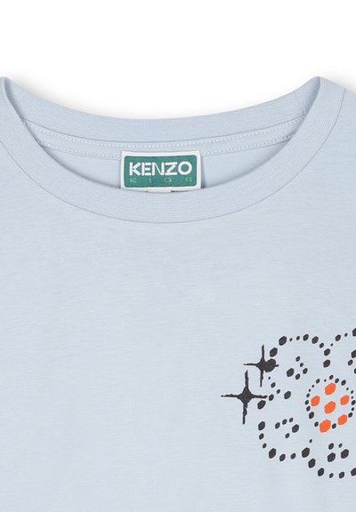 T-shirt bleu clair à manches courtes avec un col rond, arborant un motif graphique noir et orange sur le devant et une texture en coton.