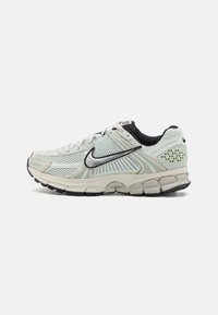 Light grey mesh running shoe with a cushioned sole, black accents, a silver Swoosh logo, and textured details on the heel and sides.