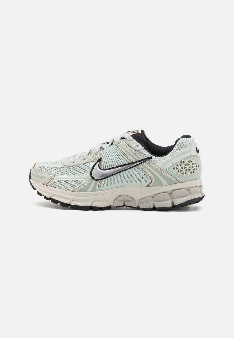 Light grey mesh running shoe with a cushioned sole, black accents, a silver Swoosh logo, and textured details on the heel and sides.