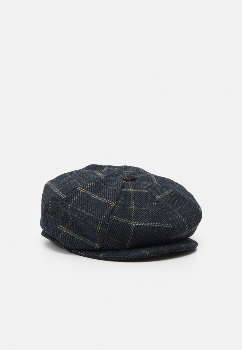 Casquette plate bleu foncé avec un motif à carreaux en lignes beiges, présentée sur un fond gris clair uni.