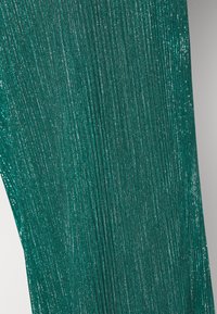 Turquoise geplooide stof met metalen draden, wat een gestructureerd patroon creëert. De plooien zijn duidelijk zichtbaar, wat diepte en visuele interesse toevoegt.