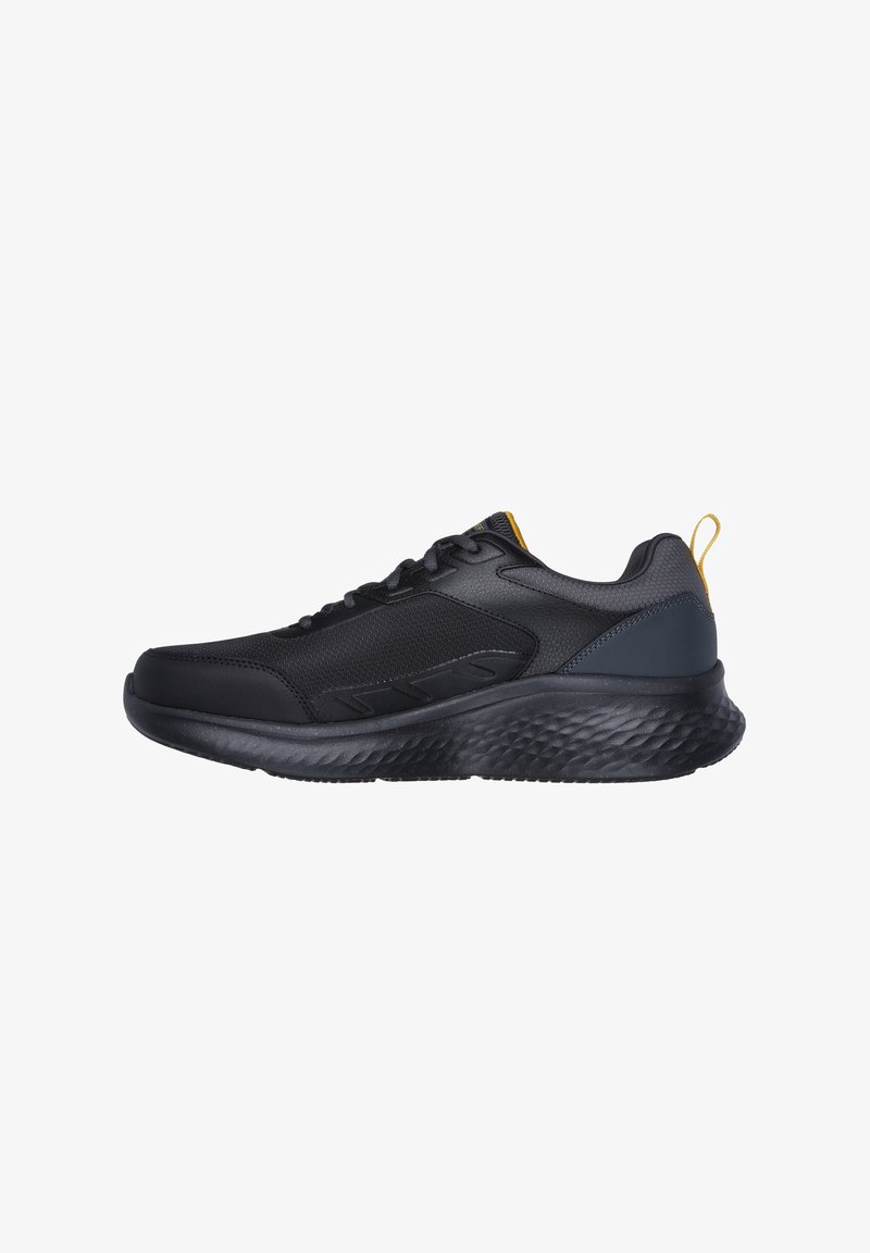 Baskets de sport noires avec semelle texturée, tige en mesh et cuir, design à lacets, et languette jaune au talon.