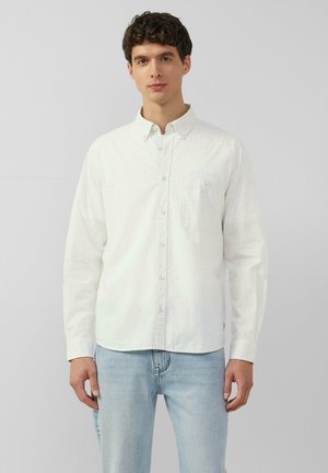 Witte button-up shirt met een gestructureerd weefpatroon, voorzien van een borstzak en lange mouwen, gedragen met lichtblauwe jeans.