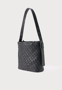 Μαύρη πλεκτή δερμάτινη τσάντα χειρός με ομαλή επιφάνεια. Διαθέτει επίπεδο μαύρο λουράκι με ρυθμιζόμενες τρύπες και δομημένο, ορθογώνιο σχήμα.