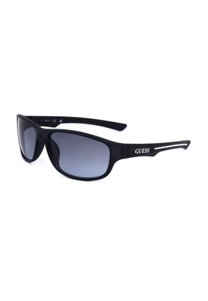 Occhiali da sole avvolgenti neri con lenti scure sfumate e logo bianco Guess sulle aste, mostrati su sfondo bianco.