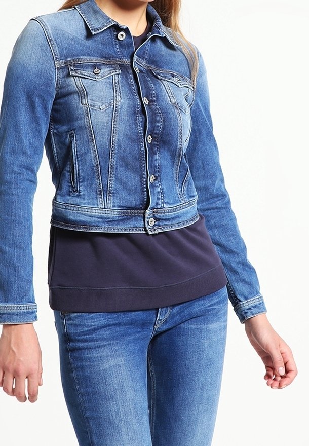 Blue denim jacket with a fitted design, front button closure, two chest pockets, and a cropped hem. Worn over a dark pullover top.