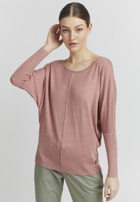 Maglione rosa morbido e dalla vestibilità ampia con scollo largo e dettagli a coste sulle maniche. Presenta una cucitura centrale e un piccolo logo accanto all'orlo.