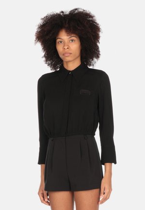 Blusa nera con maniche lunghe e colletto, dotata di una vita elastica e dettagli di tasca frontale. Tessuto liscio con un design aderente.