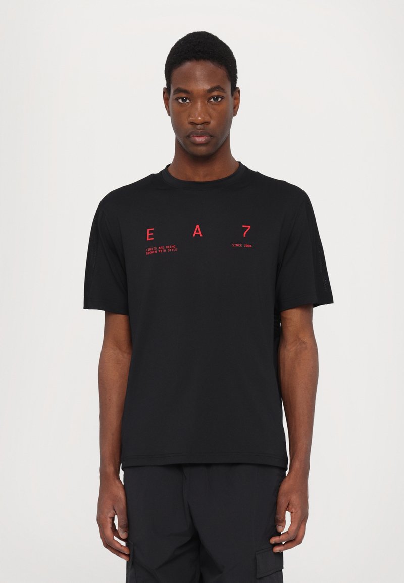 Black short-sleeve t-shirt in lightweight fabric, featuring red text "EA7" and slogan on the front. Crew neck, relaxed fit, plain design.