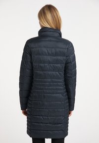 Granatowa kurtka puchowa z wysokim kołnierzem, z poziomymi przeszyciami i gładką, błyszczącą teksturą, sięgająca do połowy uda.