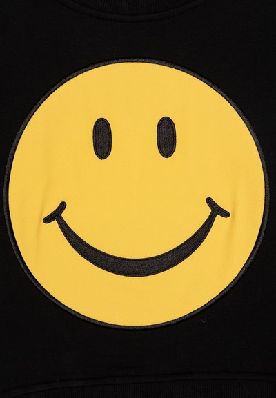 Svart sweatshirt med ett stort gult smileyansikte i grafik. Smileyansiktet har svarta broderade ögon och ett böjt leende, med en slät textur.
