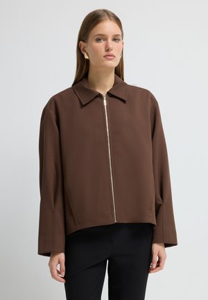 Bruine cropped jas met een rits sluiting, puntige kraag en lange mouwen. De stof lijkt textuur te hebben met een gladde afwerking.