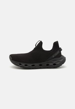 Zapatilla deportiva negra que cuenta con una parte superior de malla transpirable, suela acolchada con patrones recortados, cuello elástico y lengüeta en el talón.