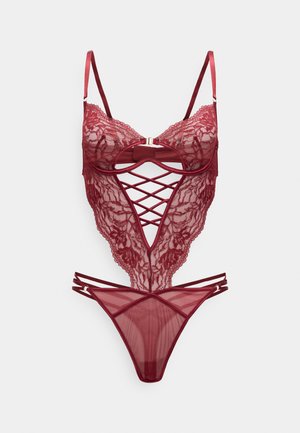 Lace body in diep rood met verstelbare bandjes, een vooraanzicht met kruispatroon en een doorschijnend mesh string onderkant.