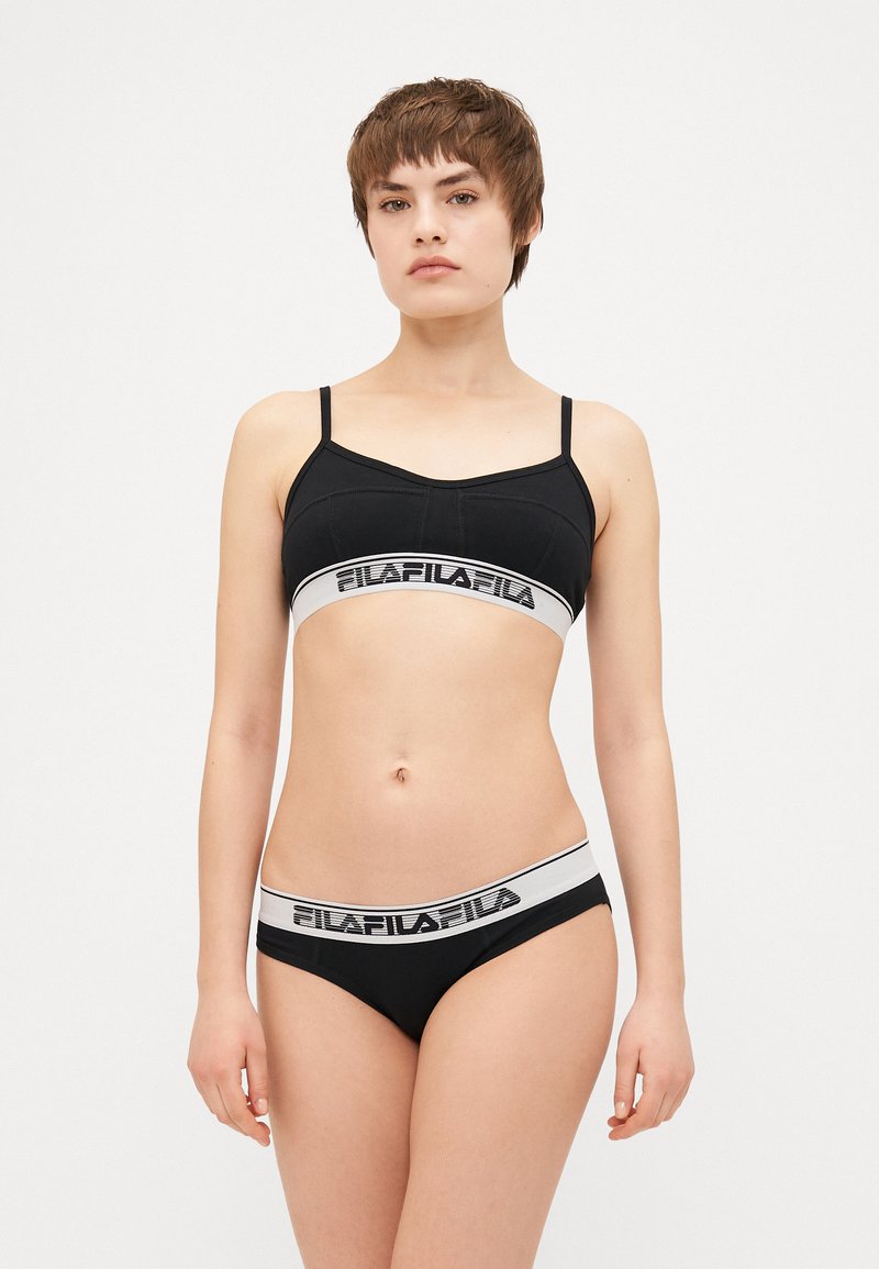 Bralette preta com alças ajustáveis, apresentando uma faixa branca com letra preta; cueca preta combinando com um design semelhante na faixa.