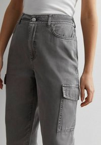 Grå cargo-byxor med lös passform. Har sidofickor, knappstängning och en urtvättad denimstruktur. Enkel sömnadsdetalj.