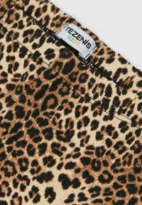 Leggings infantiles de estampado de leopardo, hechos de una tela suave; presentan una base color beige con manchas marrón oscuro y negras, cinturilla elástica y etiqueta de TEZENIS.
