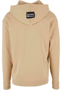 Felpa con cappuccio beige dal texture morbido, con etichetta sul retro. Design semplice con polsini e orlo a coste.
