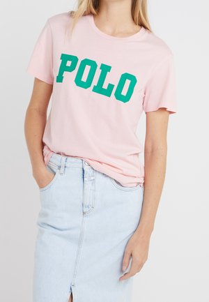 Light pink cotton t-shirt with large green "POLO" text, paired with a light denim skirt featuring a front slit and a relaxed fit.