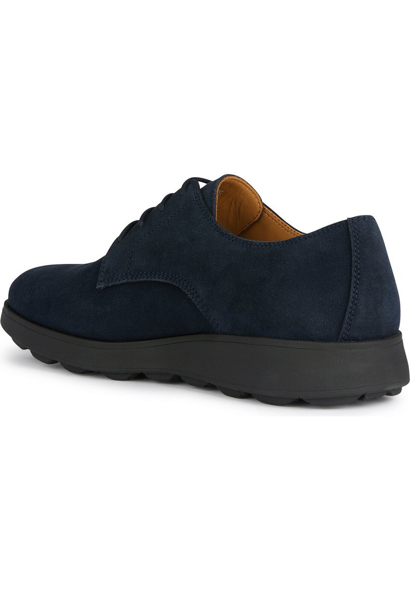 Chaussure en suede bleu marine à lacets avec un bout arrondi, intérieur contrastant beige, et une semelle en caoutchouc noir comportant des motifs de grip texturés.