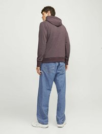 Purple hooded sweatshirt, relaxed fit, cotton blend fabric. Paired with light blue oversized jeans. White sneakers with patterned accents.
