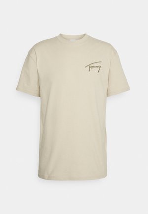 Camiseta beige de manga corta con cuello redondo y pequeño logo marrón "Tommy" bordado en el pecho izquierdo.