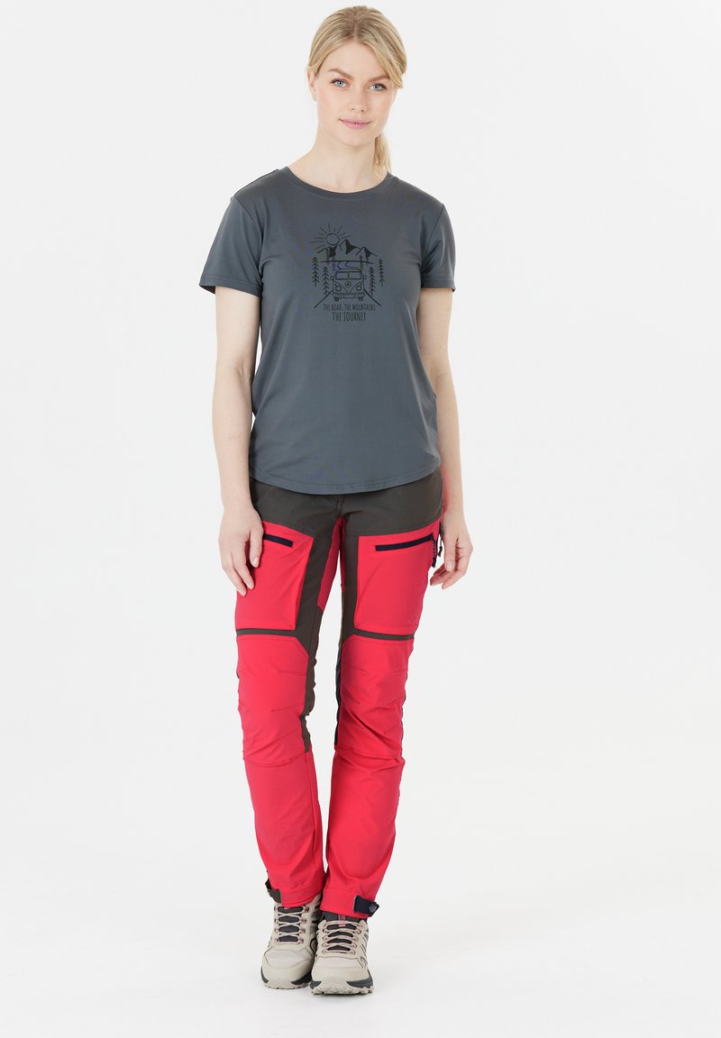 Grijs t-shirt met korte mouwen en een grafische print, gecombineerd met helderrode en donkergrijze broek met cargozakken en ritsen.