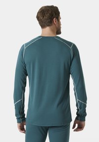 Langarmshirt gemaakt van gestructureerde teal stof met contrasterende grijze stiksels langs de schouders en zijkanten, met een ronde hals ontwerp.