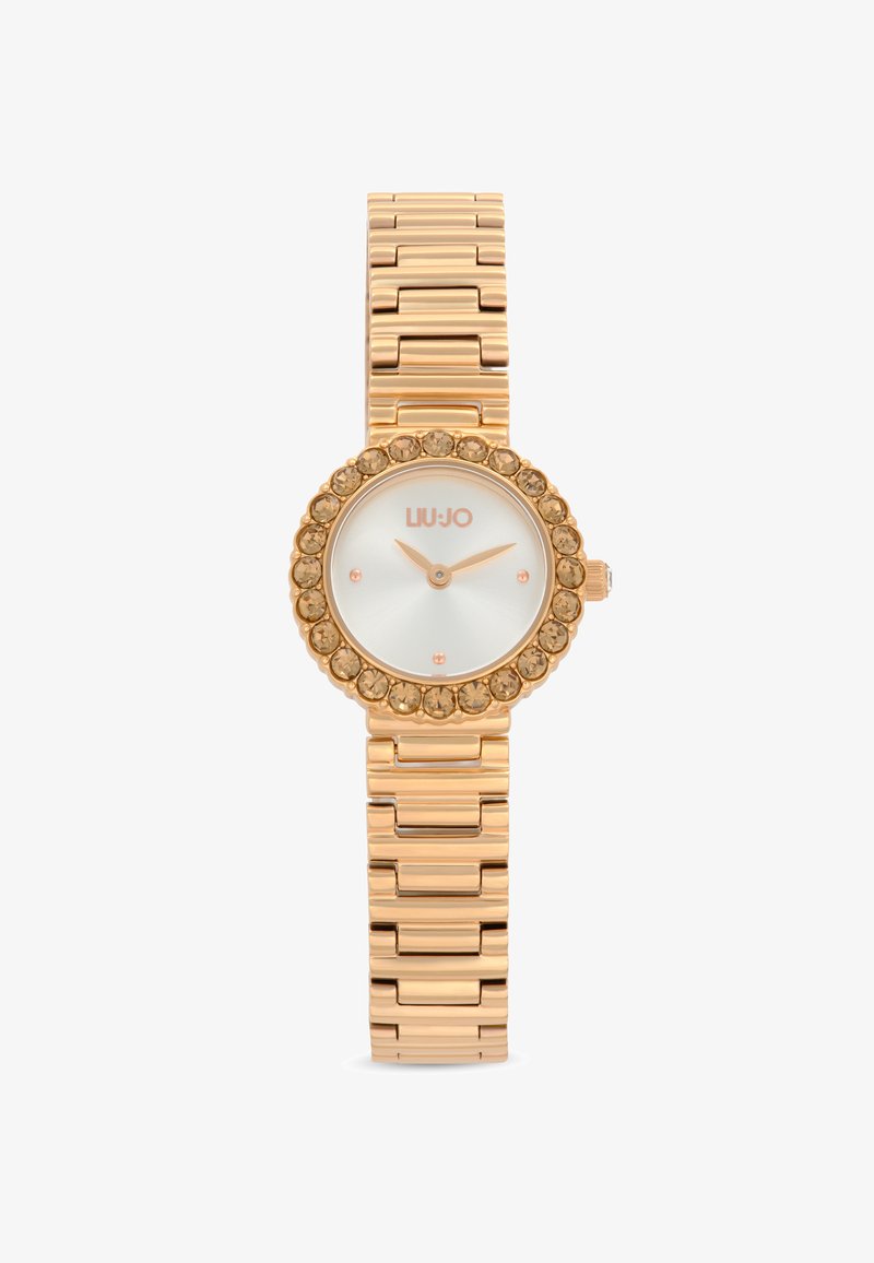 Reloj dorado con una esfera redonda, bisel adornado con cristales y una pulsera de metal pulido. Cuenta con un dial blanco con acentos en oro rosa.