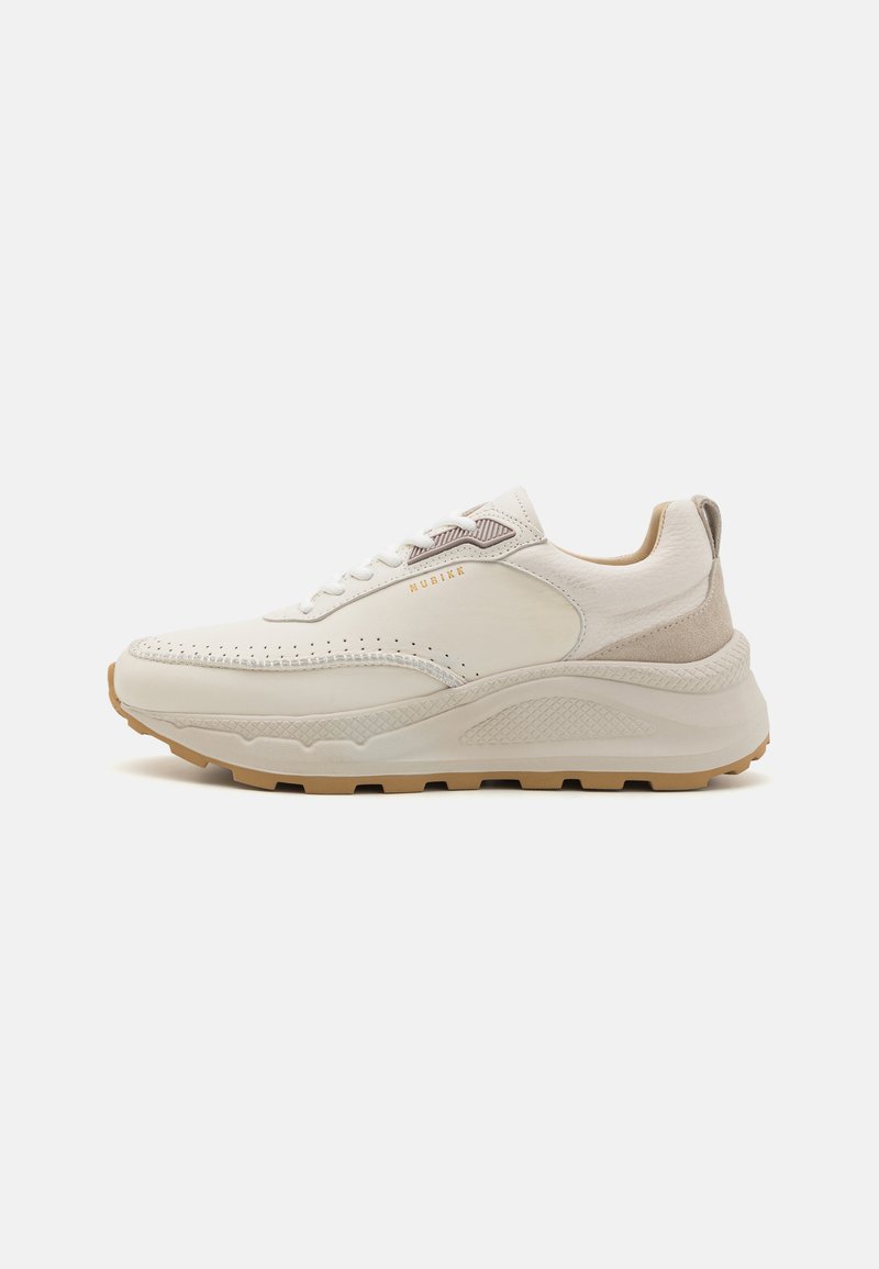 Light beige sneaker with textured leather upper, perforated detailing, and a beige rubber sole. Features flat laces and a cushioned design.
