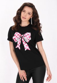 Tricou negru cu un grafic mare în formă de fundă în carouri roz și alb pe partea din față; mâneci scurte și croială lejeră.