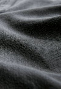 Szary materiał o gładkiej fakturze, pokazujący subtelne zagięcia i lekki połysk, co wskazuje na elastyczny i lekki materiał.