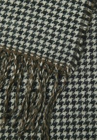 Mustvalge hunditõmmise mustriga kootud sall pruuni tislerdusega. Tekstuuriga kangas, mis tutvustab detaile käsitöö ning kontrastseid värve.