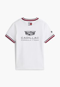 Camiseta blanca de manga corta con cuello y puños a rayas en rojo, blanco y azul marino, logotipo de Cadillac y texto "EQUIPO CADILLAC DE FÓRMULA 1" en la parte trasera.