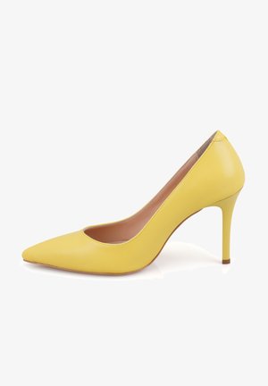 Pompe jaunes en cuir à bout pointu avec un talon fin. Texture lisse, côtés ouverts et design épuré. Présente un intérieur nude et une semelle solide.