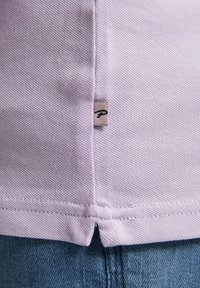 Lila bavlněná košile s texturovanou tkaninou, bočním rozparkem a malou tkanou etiketou blízko dolního švu s písmenem "P".