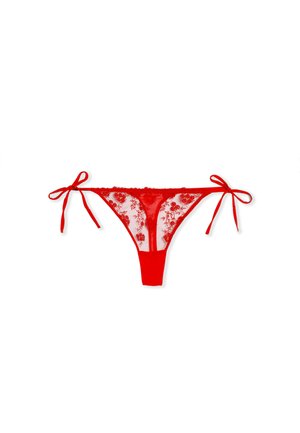 Tanga en dentelle rouge avec broderie florale transparente, nœuds ajustables de chaque côté et panneau arrière rouge uni. Texture et design délicats.