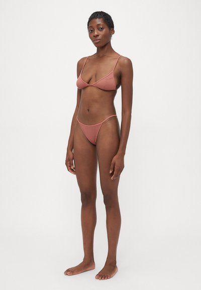 Zestaw bikini w kolorze przybrudzonego różu, z trójkątnym stanikiem i minimalnym pokryciem w formie stringów, wykonany z teksturowanej tkaniny z regulowanymi ramiączkami.