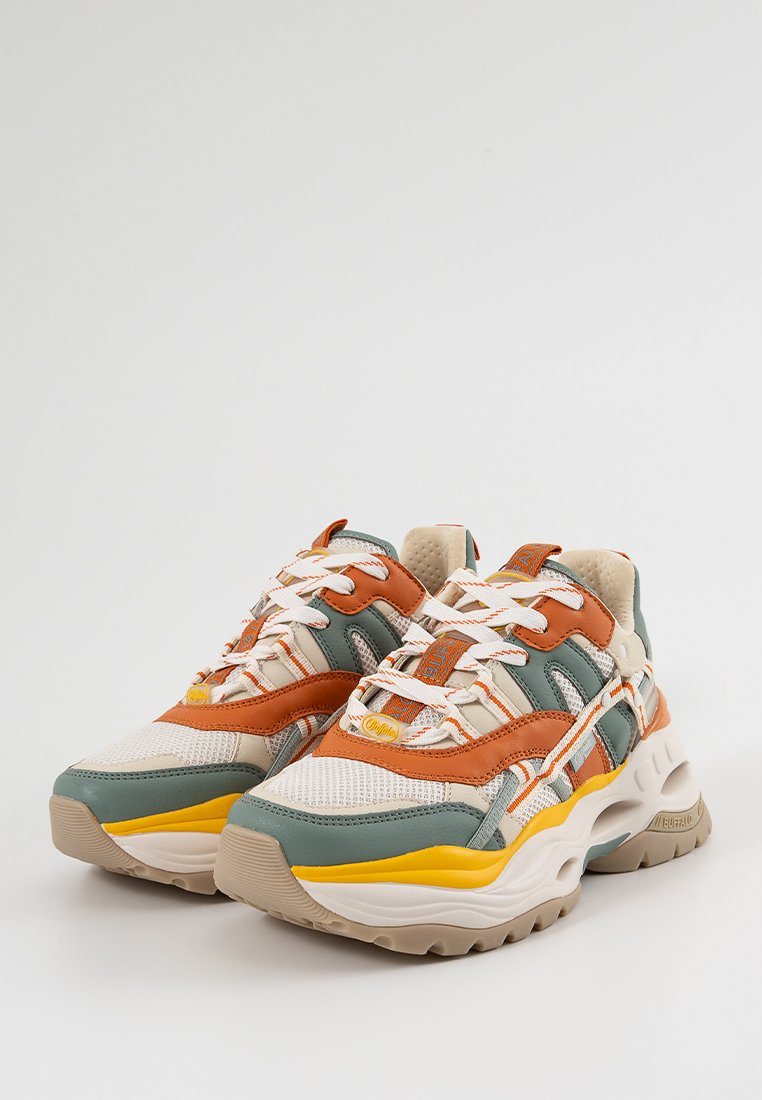Zapatillas chunky con malla beige, detalles en cuero verde y naranja, una franja amarilla y suelas gruesas beige, dispuestas de lado a lado sobre un fondo blanco.
