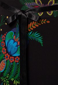 Tkanina w kwiatowy wzór o żywych kolorach, na czarnym tle, z satynowym wiązaniem przy dekolcie.