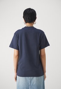 Granatowy bawełniany t-shirt z krótkimi rękawami, klasycznym okrągłym dekoltem i luźnym krojem, pokazany od tyłu na jasnym tle.