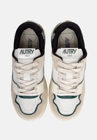 Sneakers bianchi e beige con accenti verdi. Presentano una tomaia in suede e pelle, una punta perforata e lacci testurizzati.