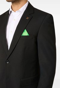 Čierny sako so strihom na mieru, s zelenou vreckovou štvorcovou šatkou, dvoma gombíkmi a oranžovým akcentom na klopni.