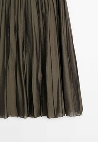 Jupe plissée en vert olive foncé, transparente, en tissu léger avec une texture froissée subtile, tombant verticalement.