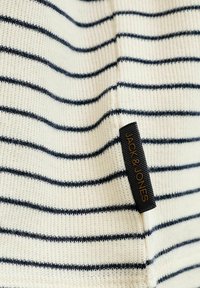 Pull en maille rayé crème et marine, présentant un motif texturé. Comprend une étiquette noire avec "JACK & JONES" en lettres dorées.