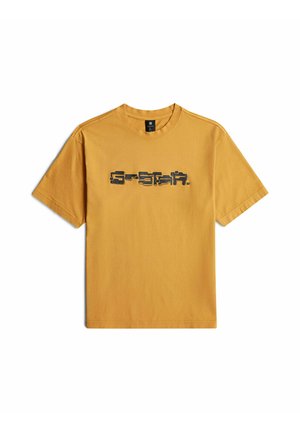 T-shirt jaune moutarde à manches courtes avec un logo texte stylisé noir centré sur la poitrine.
