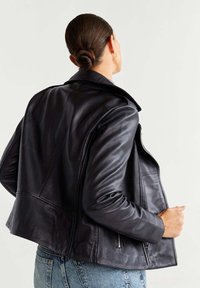 Černá kožená bunda s přiléhavým střihem, širokým límcem, viditelným šitím a kapsami na zip. Hladký povrch a zkrácená délka.