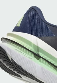 Close-up of navy blue sneaker heel with mesh upper, light green and white sole, and "REPETITOR" printed on the midsole.