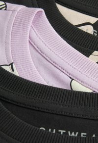 Tre scollature di t-shirt sovrapposte: nera, viola chiaro e nera. Bordo a coste testurizzato, con una che presenta un motivo a fumetti sottostante.